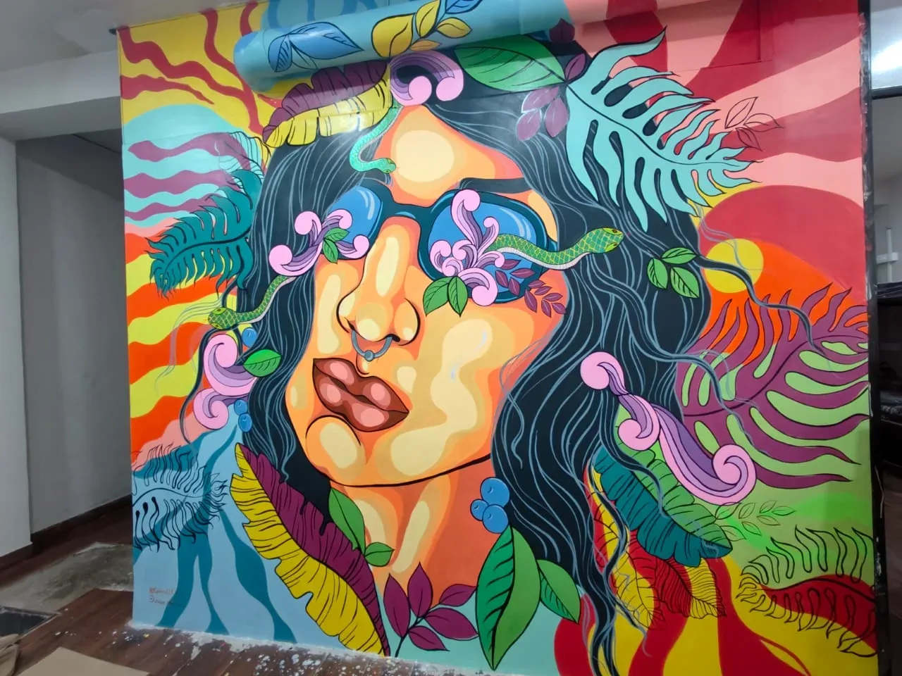 A colourful painted face surrounded by leaves and flowing floral shapes