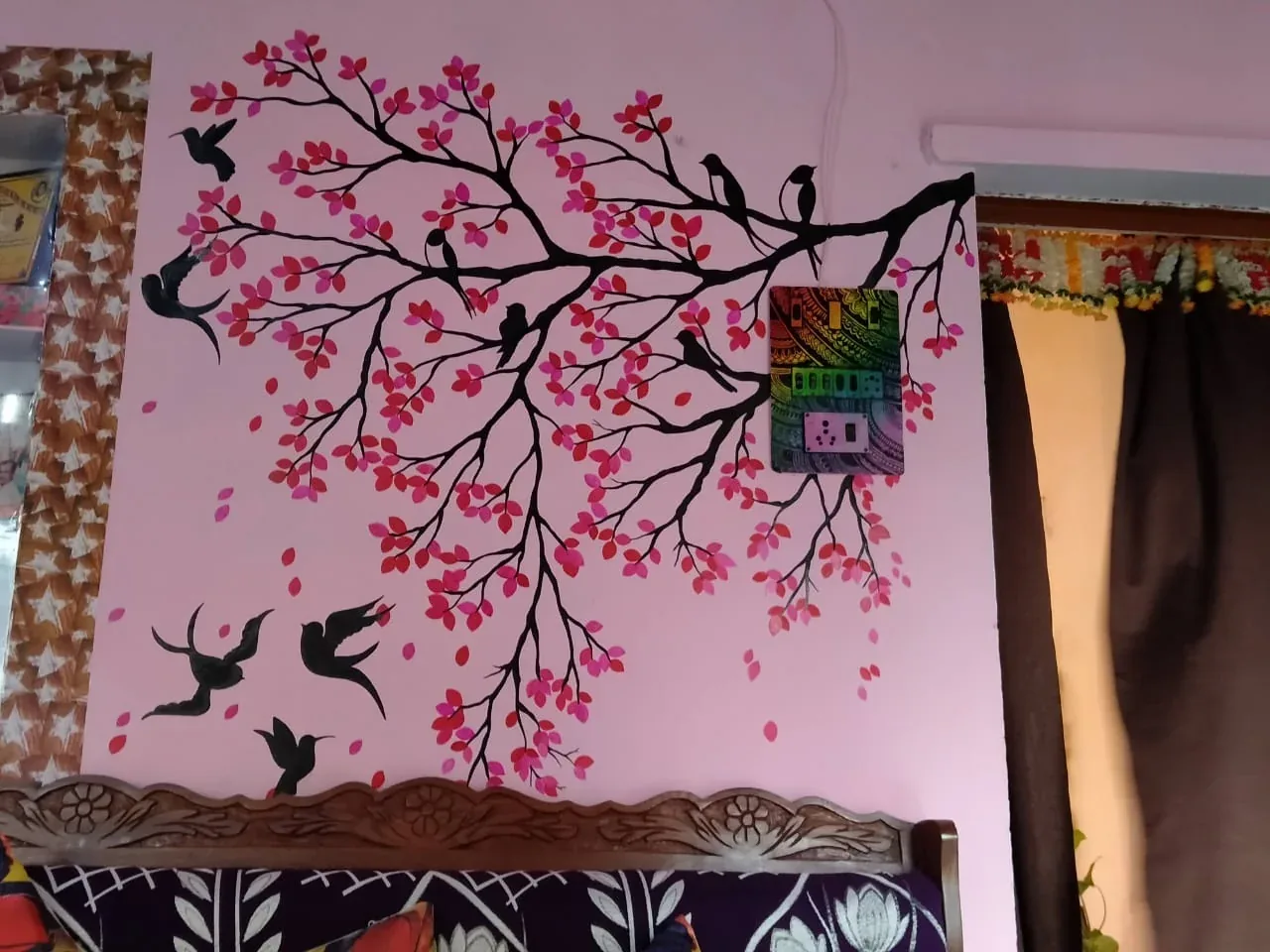 Dark painted branches with pink blossoms and birds across a pink wall