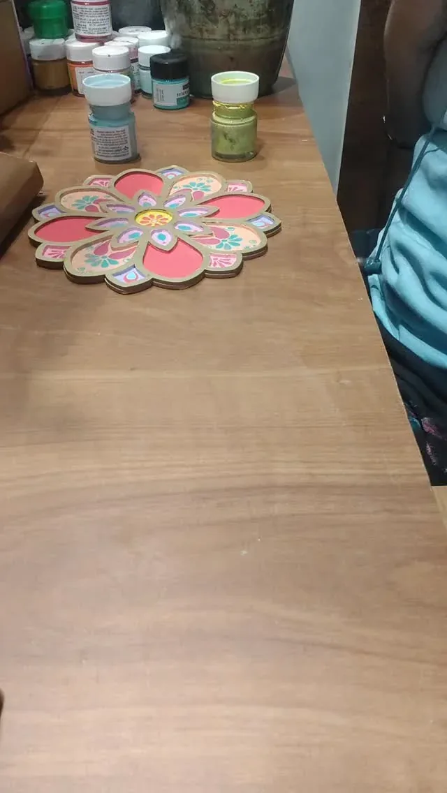 A multicoloured flower-shaped painted decorative piece beside paint jars