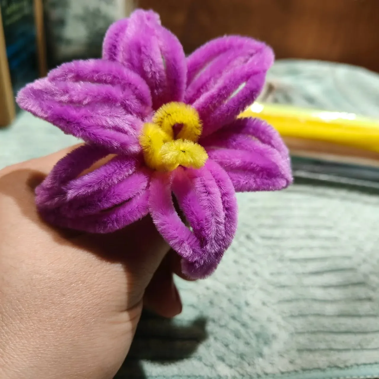 A purple handmade flower with a yellow centre