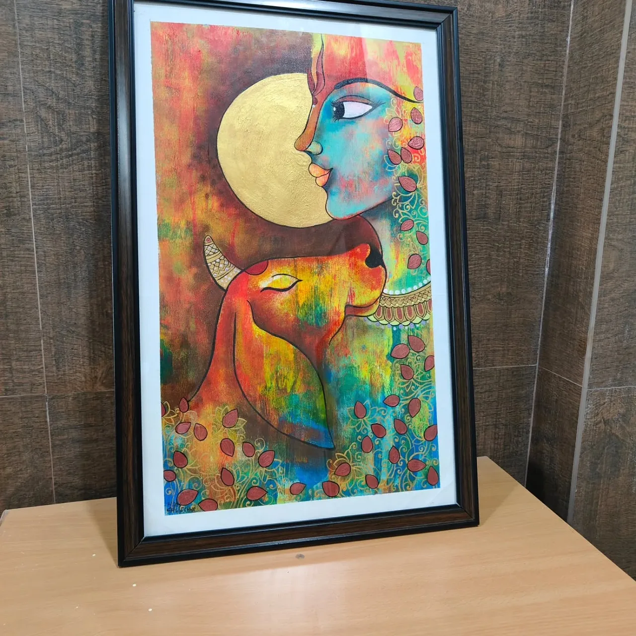 A framed painting of a face beside a yellow circle with colourful floral details